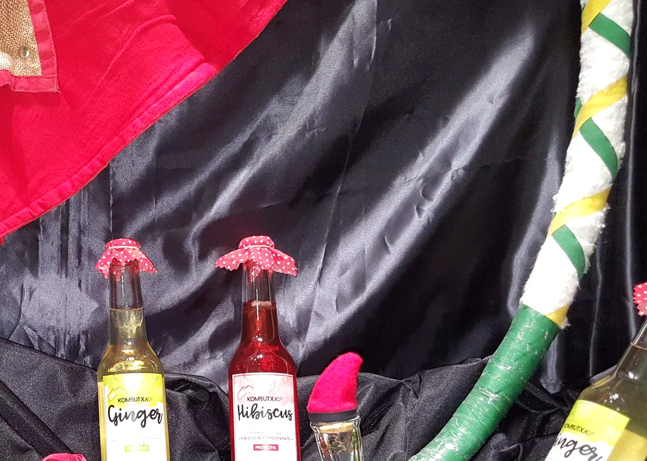 Aparador de la botiga amb ampolles de begudes de gingebre i d'hibisc sobre tela fosca.